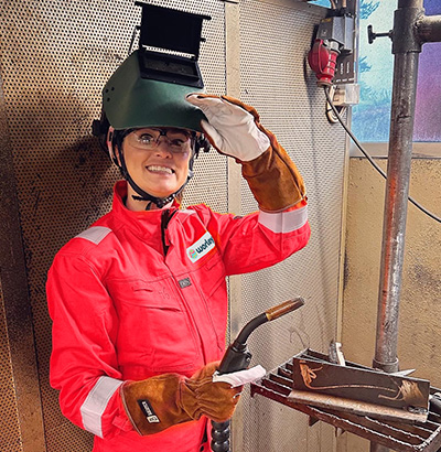 Angela is in PPE suit holding welding tool