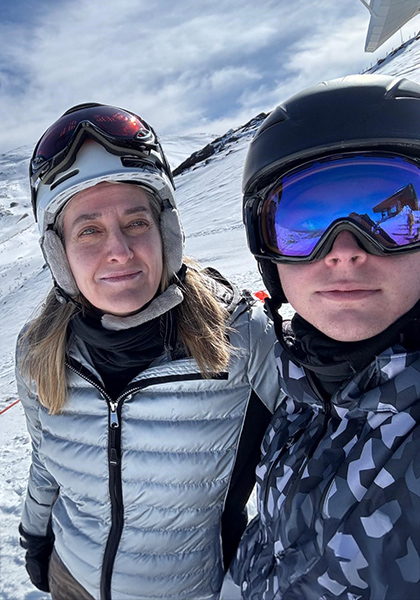 Carmen and her son dressed in skiing wear on the snow.