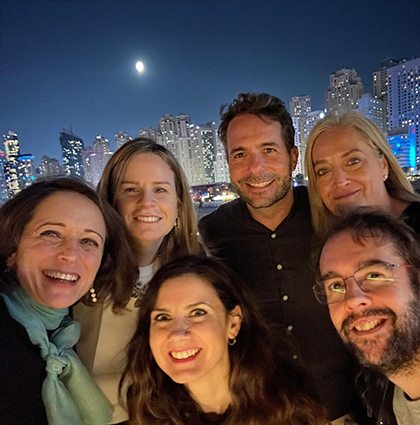 Carmen with a group of 5 people in front of a night time city skyline.