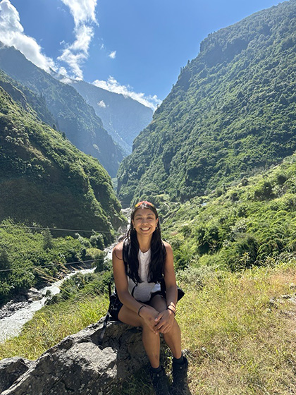 Claire sitting on a rock in front of a steep mountain range.