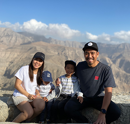 Enrica with her partner and two children in front of a large mountain range.