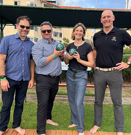 Erica standing with 3 people holding bowls on a bowling green.
