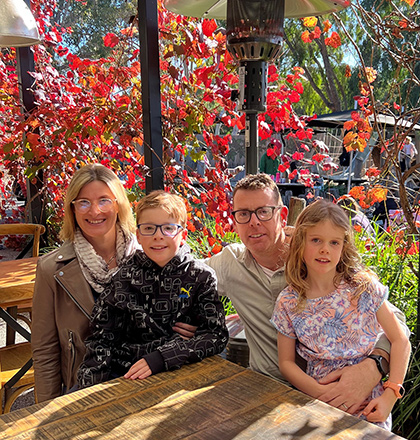 Erica sitting outside at a table with husband and two children.