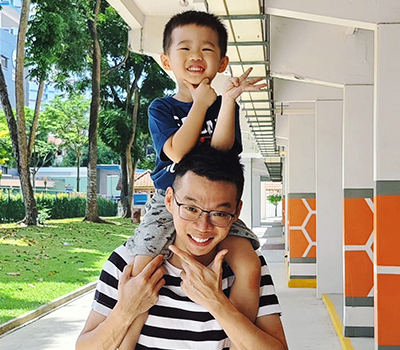 Guan carrying his cheerful young son on his shoulders outdoors
