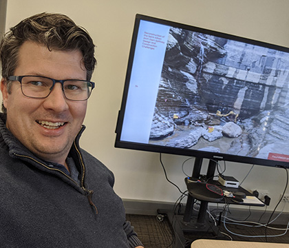 Iain working from home posing next to his screen