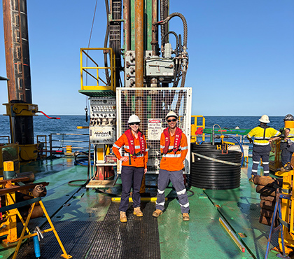 Kaitlin with a colleague wearing PPE standing on an offshore platform.