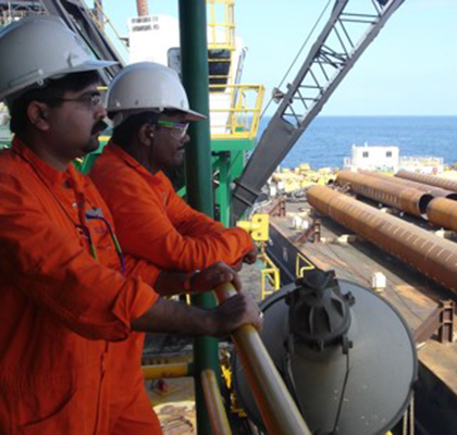 Raj and a colleague wearing PPE on an offshore platform looking out.