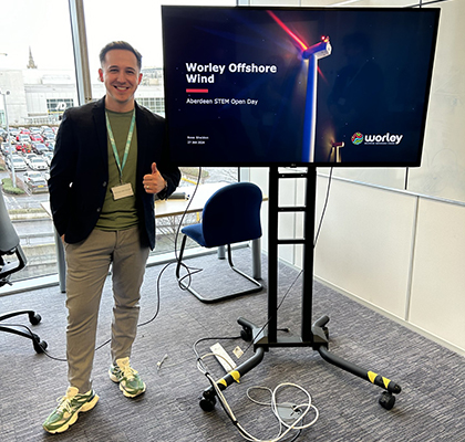 Ross next to a large TV screen, presenting on Offshore Wind.