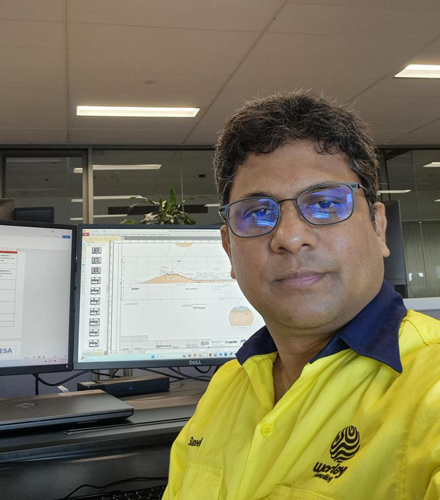 Suneel in T-shirt with the Worley logo on it and sitting at an office desk