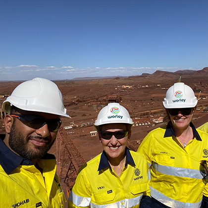 Vikki standing outside in a mine site with two people wearing hard hats.