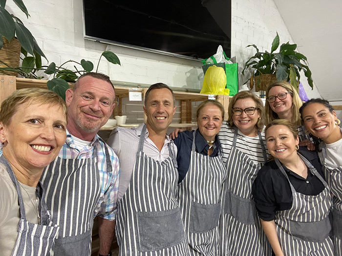 Vikki standing with a group of 7 people all wearing aprons.