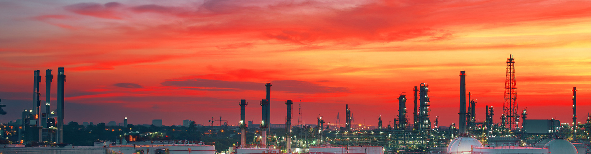 Oil refinery petrochemical plant with a vibrant orange sky.