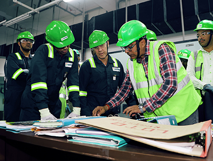 Several engineers wearing PPE bending over to look at paperwork.