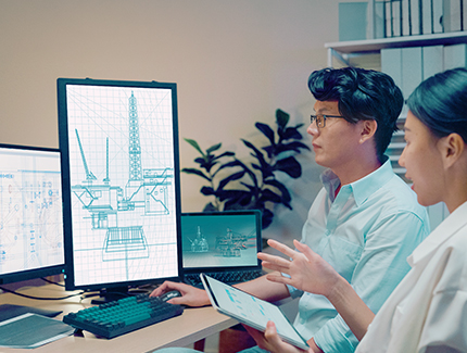 Two people sitting together in front of multiple screens designing on CAD.