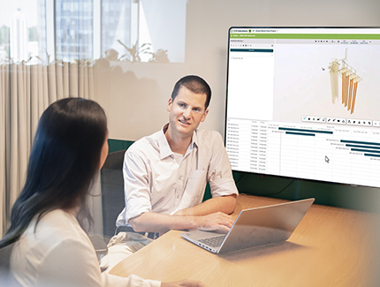 Two Worley people sitting together in front of a laptop and large screen.