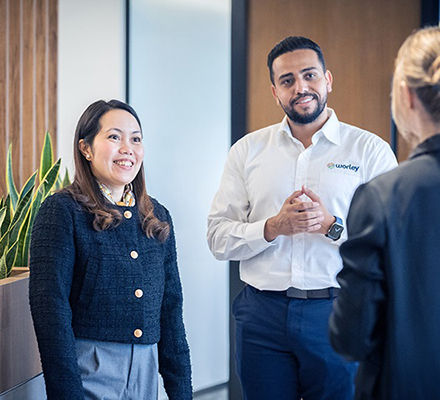 Three Worley people standing together talking in the office.