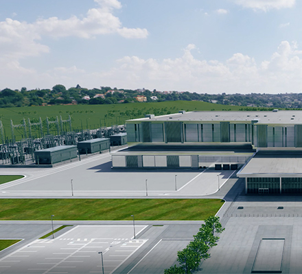 Large, modern data center campus with multiple low-rise buildings, electrical substations, and surrounding green fields.