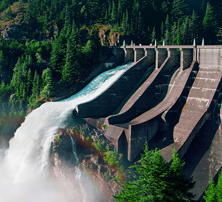 Hydropower structure in a forested mountain canyon with gushing water running down.