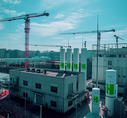 Plant with white cylindrical storage tanks with H2 embossed on them.