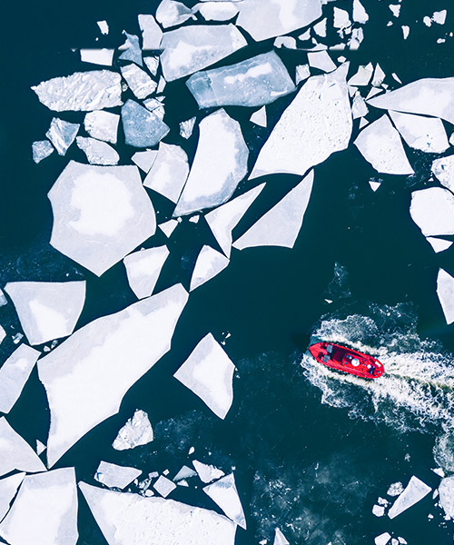 Bright boat cruising through water with shattered pieces of ice.