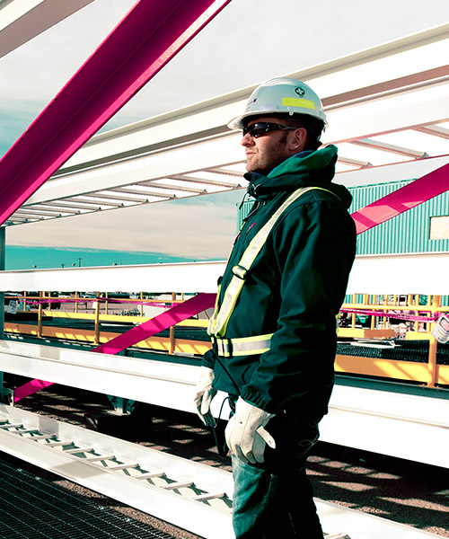 Construction worker wearing a hard hat standing next to a large metal structure.