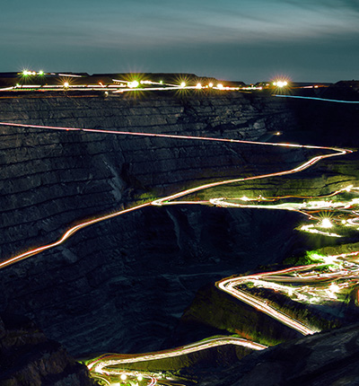 Night view of an open-pit mine with winding roads illuminating by vehicle lights