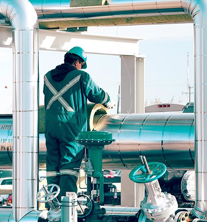 Construction worker wearing a hard hat standing next to a large metal structure.