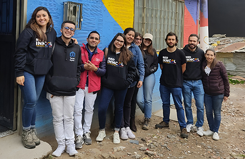 Group of students standing together outside a colorful building.
