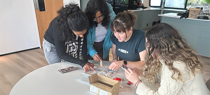 Group of four young women doing a STEAM activity at a desk.