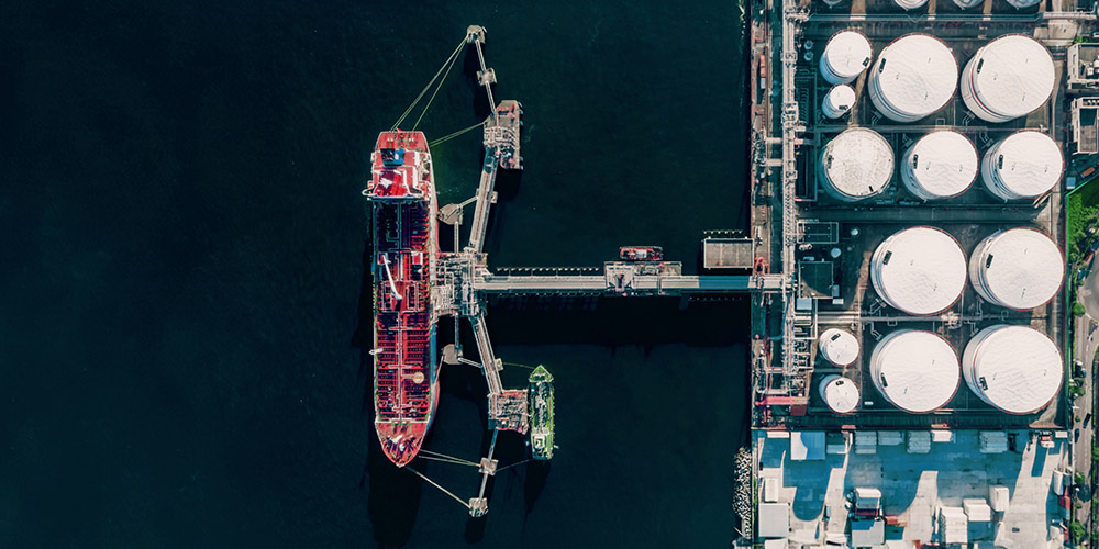 Aerial view of large ship next to an oil storage tanks.