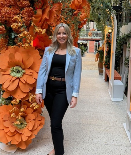 Cheryl standing in a passageway filled with flowers.
