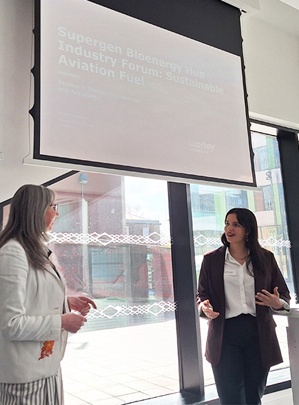 Claudia presenting at the front of a room alongside a colleague.