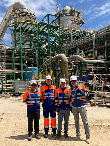 Gavin standing with three colleagues wearing PPE in front of a large steel structure.
