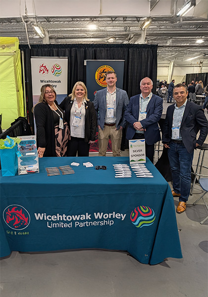 Team standing behind a booth at an industry event with Wicehtowak Worley Limited Partnership signage.