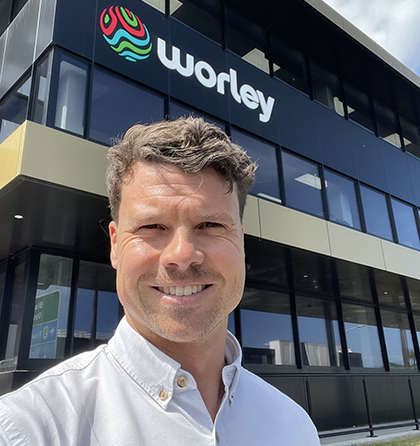Tom standing outside an office building with the Worley logo on it.