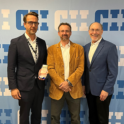 Tony holding an award standing with two other colleagues.