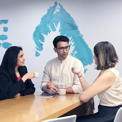 Three Worley people sitting together at a table talking.