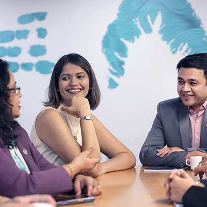 Three people sitting together at a table talking.