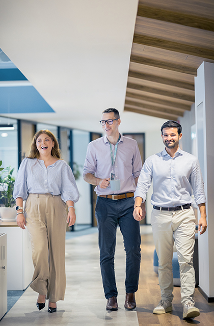 Three Worley people walking together smiling in an office.
