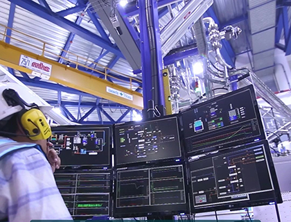 Person sitting in front of two computer screens in a factory.