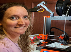 Dana sitting in front of her 3D printer.