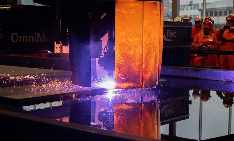 Group of Worley Rosenberg people watching a machine cutting steel.