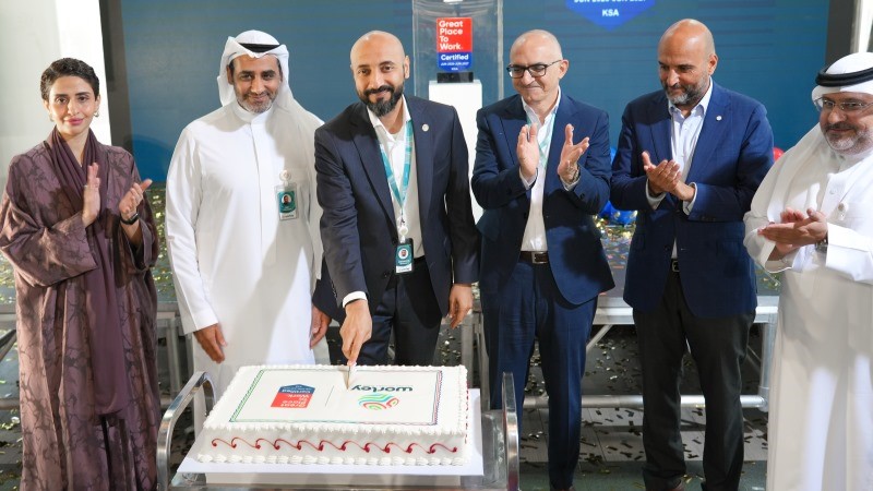 Leaders of the Saudi Arabia office cutting a cake to celebrate.