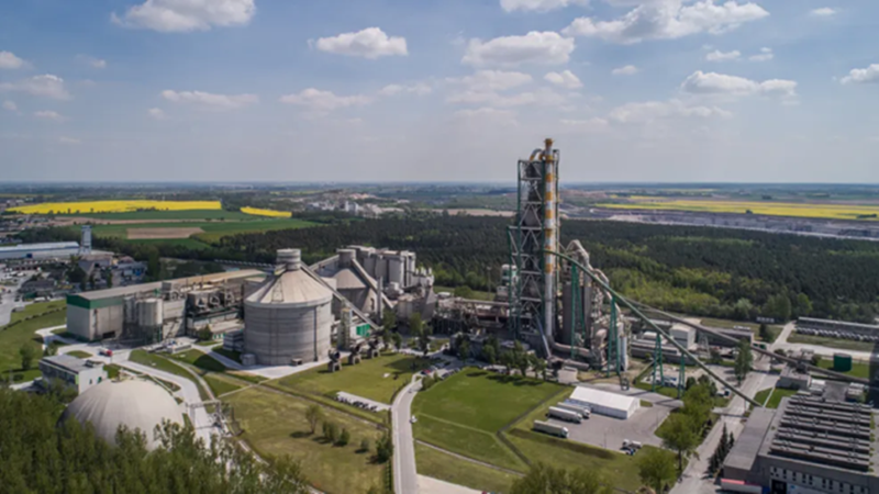 Aerial view of a cement production facility with processing towers and silos.