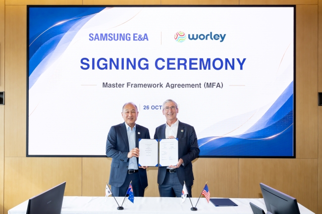 Mark Trueman and Hong Namkoong standing together holding the signed agreement.