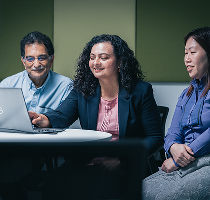Three Worley people sitting together in front of a laptop smiling.