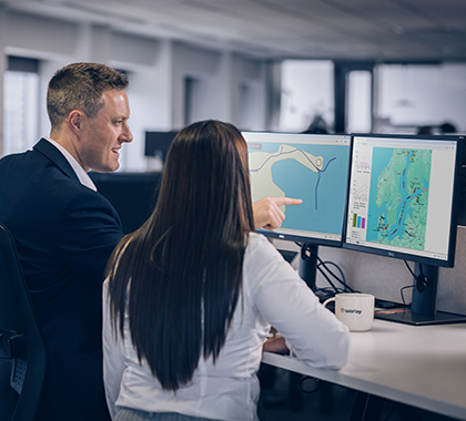 Two people in an office looking at data on a computer screen.