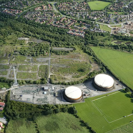 Aerial view of a gas plant set amongst green landscape.