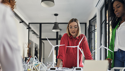 Two women standing at a table looking at model wind turbines.