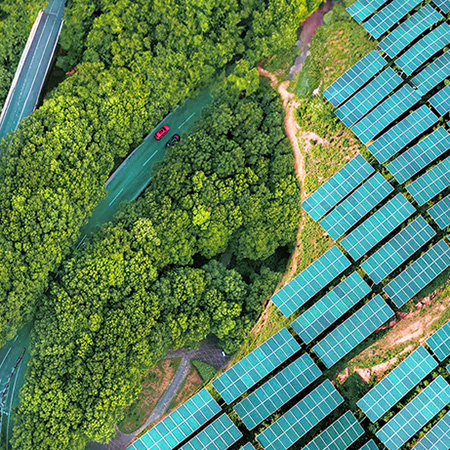 Aerial view of solar panels and two roads next to a forest.